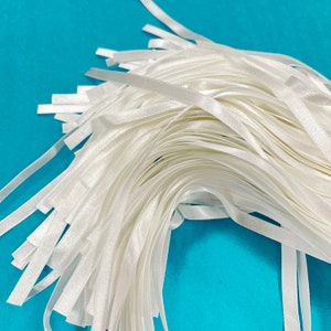 May include: A pile of white satin ribbon, ideal for crafting, gift wrapping, or adding a touch of elegance to any project.