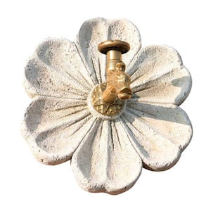 Può includere: Una fontana da parete in ceramica bianca a forma di fiore con un rubinetto in ottone.