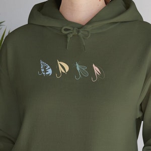 May include: A green hooded sweatshirt with a row of five colorful fishing lures embroidered on the front.