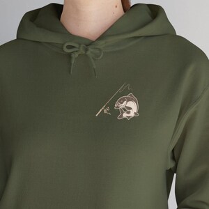 May include: A dark green hooded sweatshirt with a pocket on the front. The sweatshirt has a small embroidered design of a fish on a fishing line.