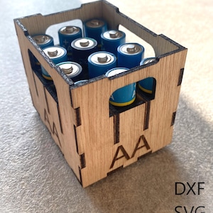 Puede incluir: Una caja de madera con las letras "AA" impresas en el lateral, llena de pilas AA azules.