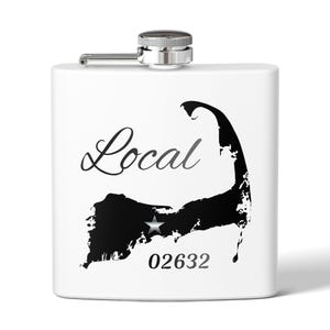 May include: White hip flask with a silver cap and hinged closure. The flask has a black coastline graphic with a star and the word "Local" in script. The postcode "02632" is printed below the coastline.