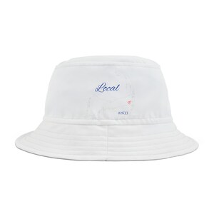 Pode incluir: Chapéu branco de pescador com um contorno azul do estado de Massachusetts e a palavra "Local" em escrita azul. O contorno inclui um pequeno coração vermelho. O número "02633" está impresso em preto abaixo do coração.