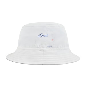 Pode incluir: Chapéu branco de pescador com um contorno azul de Cape Cod e a palavra "Local" em escrita azul. O contorno inclui um pequeno coração vermelho e o número 02653.
