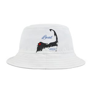 Pode incluir: Chapéu branco de pescador com um contorno preto de Cape Cod e a palavra "Local" em escrita azul. Um coração vermelho está no centro do contorno. O texto "02532" está abaixo do contorno.