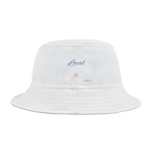 Pode incluir: Chapéu de balde branco com um contorno azul de Cape Cod e o texto "Local" em escrita azul. Um coração vermelho está dentro do contorno. O texto "02632" está abaixo do coração.