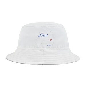 Pode incluir: Chapéu branco de pescador com um contorno azul de um estado e a palavra "Local" em azul cursivo. O contorno do estado tem um coração vermelho dentro. O número 02631 está impresso abaixo do coração.