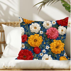 Puede incluir: Un cojín cuadrado con un vibrante estampado floral sobre un fondo azul marino intenso. El diseño incluye grandes crisantemos y dalias detallados en tonos amarillo brillante, rojo intenso, rosa suave y blanco nítido con hojas verdes.