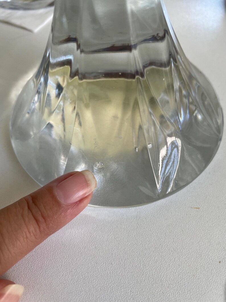 May include: Clear glass vase with a flared base and a textured, ridged design. The vase has a wide, circular base and a slender neck, ideal for displaying flowers or as a decorative piece.