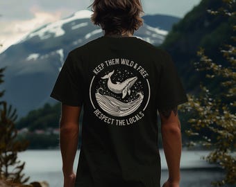 May include: Black t-shirt with a white graphic of a whale breaching the ocean's surface, surrounded by stars. The text reads "KEEP THEM WILD & FREE" and "RESPECT THE LOCALS" in a circular design. The shirt is worn by a person.
