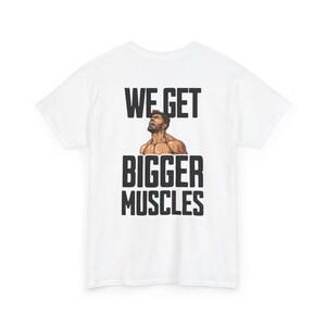 May include: White t-shirt with the text "WE GET BIGGER MUSCLES" in black block letters. A muscular man graphic is between the words. The shirt is made of a soft material.