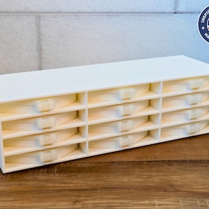 Puede incluir: Organizador de plástico blanco con 15 compartimentos, cada uno con una pequeña tapa con bisagras. El organizador está hecho en los Estados Unidos.