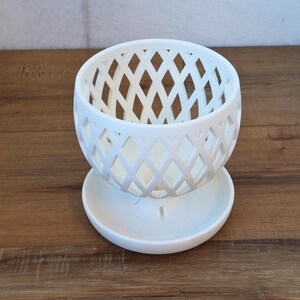 May include: White ceramic planter with a diamond-shaped lattice design. The planter has a matching saucer.