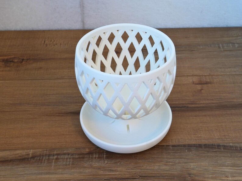 May include: White ceramic planter with a diamond-shaped lattice design. The planter has a matching saucer.