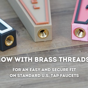 May include: Three different colored tap handles with brass threads. The handles are black, beige, and pink. The text "NOW WITH BRASS THREADS!" is displayed below the handles. The text "FOR AN EASY AND SECURE FIT ON STANDARD U.S. TAP FAUCETS" is displayed below the first line of text.