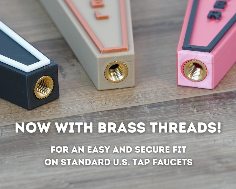 May include: Three different colored tap handles with brass threads. The handles are black, beige, and pink. The text "NOW WITH BRASS THREADS!" is displayed below the handles. The text "FOR AN EASY AND SECURE FIT ON STANDARD U.S. TAP FAUCETS" is displayed below the first line of text.