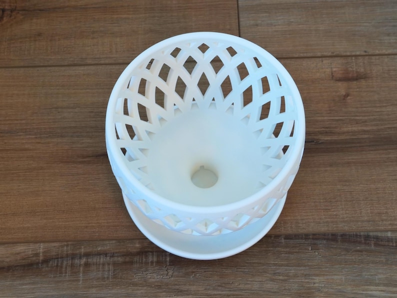 May include: White ceramic planter with a decorative lattice design. The planter has a drainage hole in the bottom.