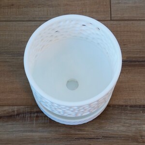 May include: White ceramic planter with a decorative, textured design. The planter has a drainage hole at the bottom.