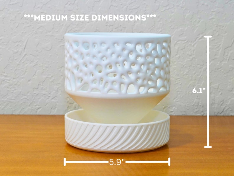 May include: White ceramic planter with a decorative, openwork design. The planter has a removable bottom tray. The planter measures 6.1 inches tall and 5.9 inches wide.