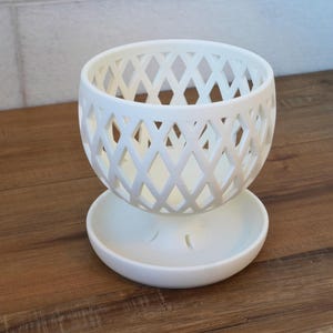May include: White ceramic planter with a diamond-shaped lattice design. The planter has a separate saucer.
