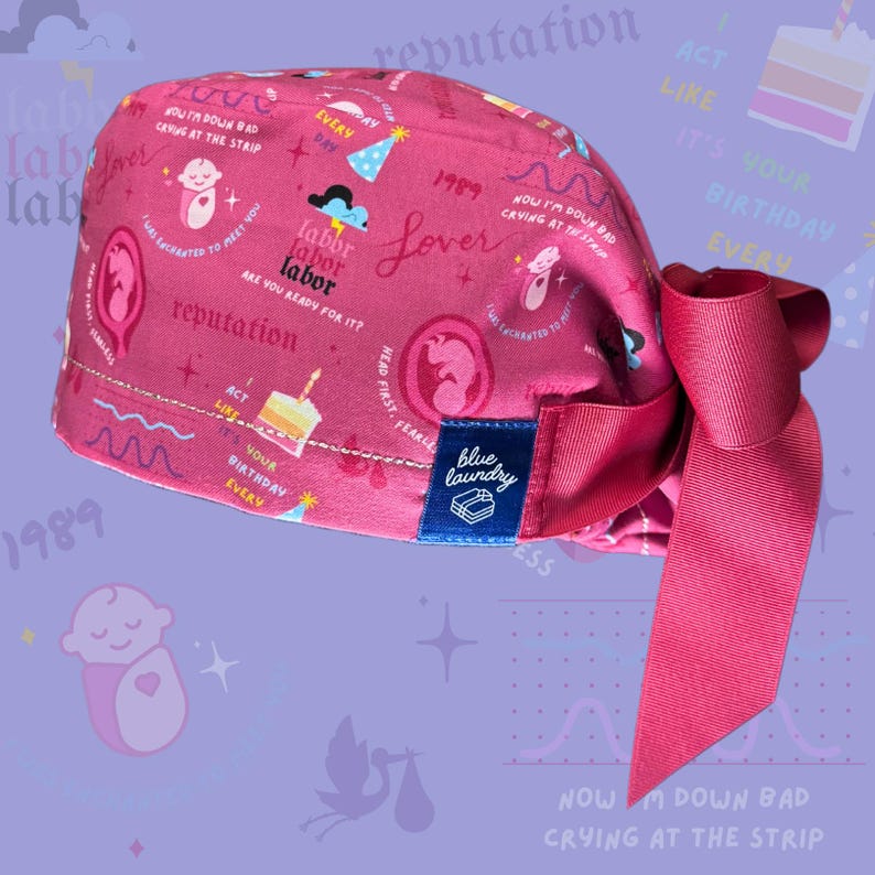 K&ouml;nnte beinhalten: Eine rosafarbene chirurgische M&uuml;tze mit einem bunten Muster, das ein Baby, einen Kuchen und den Text "labor labor labor", "Lover", "reputation", "1989", "Act Like It's Your Birthday Every Day", "Now I'm Down Bad Crying at the Strip" und "Head First Fearless" zeigt. Die M&uuml;tze hat ein blaues Etikett mit dem Text "blue laundry".