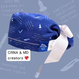 May include: Blue surgical scrub hat with white ties. The hat has a variety of phrases printed on it, including "Not me leaving at 7:08 for a 7:00 case" and "It's ok I just watched a YouTube video on this". The hat also has a blue laundry tag with the words "blue laundry" printed on it.