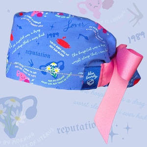May include: Blue surgical scrub hat with a pink ribbon tie. The hat has a white and pink uterus graphic and text that reads "Lover", "1989", "reputation", "the hospital was a drag", "worst sleep that I ever had", "cause baby now we got bad blood", "my ovary is looking a lot like a tragedy now", "gone was any trace of uterus", "I don't sing", "blue laundry".