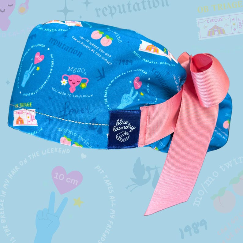 May include: A blue scrub cap with a pink bow. The cap features various graphics, including peaches, hearts, and text like "reputation" and "Lover." A pink heart graphic shows "10 cm."