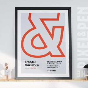 Könnte beinhalten: Gerahmtes Poster mit einem großen orangefarbenen kaufmännischen Und-Zeichen auf grauem Hintergrund. Das Poster zeigt auch den Text "Fractul Variable" und einen vollständigen Satz von Alphabet und Zahlen. Das Poster ist in einem schwarzen Rahmen.