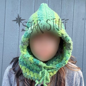 May include: A green and yellow crocheted hood with a pointed top and a scarf-like neck. The hood is made of chunky yarn and has a textured appearance. The text "STAR to STUFF" is visible on the hood.