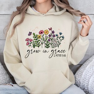 May include: A beige hoodie with a floral design and the text "grow in grace 2 Peter 3:18" printed on the front.