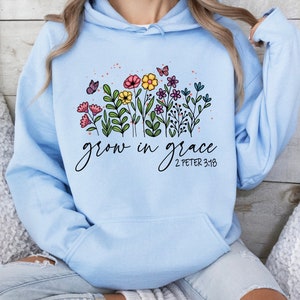 May include: Light blue hooded sweatshirt with a floral design and the text "grow in grace 2 Peter 3:18".