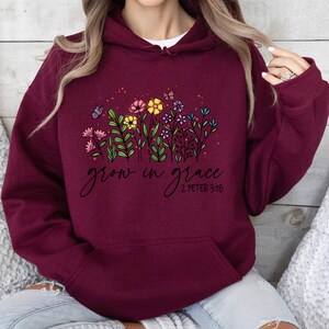 May include: Burgundy hooded sweatshirt with a floral design and the text "grow in grace 2 Peter 3:18".