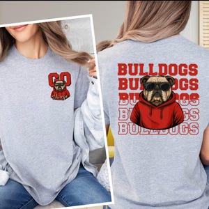 May include: Heather gray sweatshirt featuring a bulldog graphic. The front has a red "GO Dawgs" design with a bulldog wearing sunglasses. The back displays "BULLDOGS" repeated vertically with a bulldog in a red hoodie.