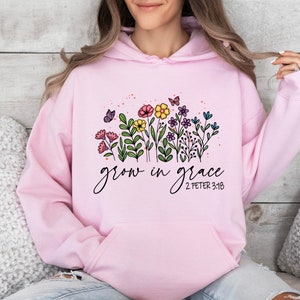 May include: Pink hoodie with a floral design and the text "grow in grace 2 Peter 3:18".