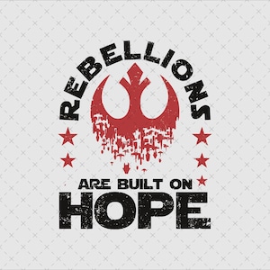May include: A distressed graphic design featuring the text "REBELLIONS ARE BUILT ON HOPE" in black, with a red symbol and stars. The design has a vintage, worn look, set against a light gray background.