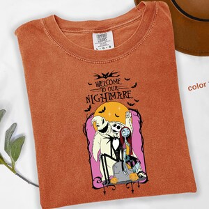 Puede incluir: Una camiseta color &ntilde;ame con un gr&aacute;fico de "Pesadilla antes de Navidad". El dise&ntilde;o incluye a Jack Skellington, Sally y Oogie Boogie, con el texto "Welcome to our Nightmare" y murci&eacute;lagos.