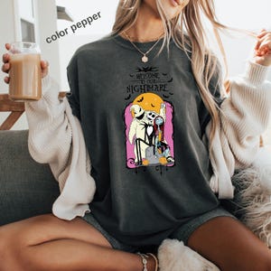 Puede incluir: Sudadera gris oscuro con un gr&aacute;fico de Jack Skellington y Sally de The Nightmare Before Christmas, con el texto "Welcome to our Nightmare". El dise&ntilde;o incluye una luna llena y murci&eacute;lagos.