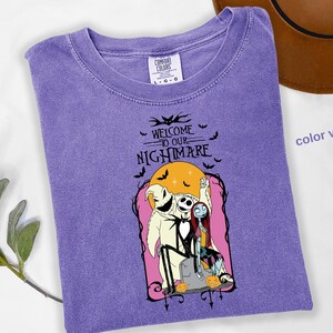 Puede incluir: Camiseta violeta Comfort Colors con un gr&aacute;fico de "Pesadilla antes de Navidad". El dise&ntilde;o incluye a Jack Skellington, Sally y Oogie Boogie con el texto "Welcome to our Nightmare" y murci&eacute;lagos.