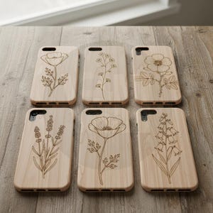 Puede incluir: Seis fundas de tel&eacute;fono de madera clara con dise&ntilde;os florales grabados, incluyendo amapolas y lavanda. Los dise&ntilde;os bot&aacute;nicos est&aacute;n grabados en la superficie, creando una est&eacute;tica natural y r&uacute;stica.