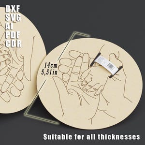 May include: Two light-colored wooden circles with a hand-drawn design of adult and child hands holding each other. The text "DXF SVG AI PDF CDR" is in the upper left. The text "14cm 5.51in" is near the center. The text "Suitable for all thicknesses" is at the bottom.