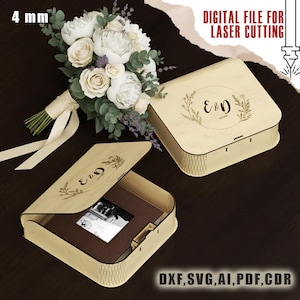 Puede incluir: Dos cajas de madera de color claro, una abierta, que muestran un marco de fotos. Las cajas tienen diseños florales grabados y las letras "E&D". Un ramo de flores blancas y vegetación está en el fondo. El texto dice "DIGITAL FILE FOR LASER CUTTING" y "DXF, SVG, AI, PDF, CDR".