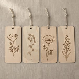 Puede incluir: Cuatro marcap&aacute;ginas de madera con dise&ntilde;os florales. Cada marcap&aacute;ginas presenta una ilustraci&oacute;n bot&aacute;nica diferente: una amapola, una ramita de flores peque&ntilde;as, otra amapola y una campanilla. Cada uno tiene un lazo de cuerda natural para colgar.
