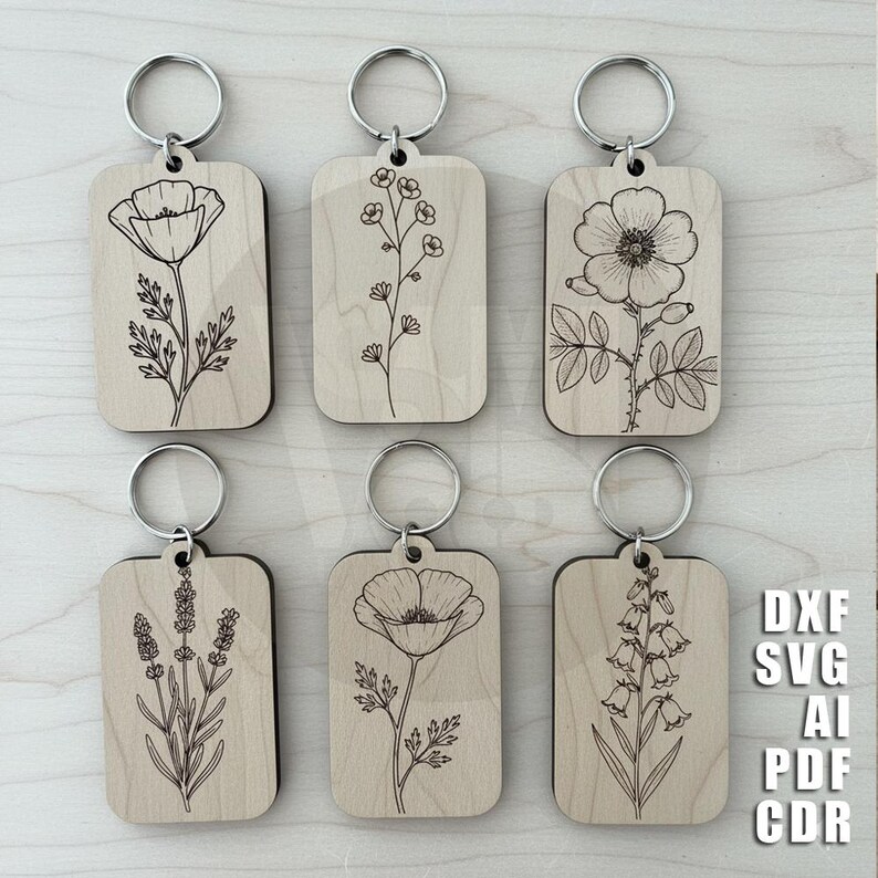 Puede incluir: Seis llaveros de madera con dise&ntilde;os florales grabados, incluyendo amapolas y lavanda. Cada llavero tiene un anillo plateado. Los llaveros son rectangulares con esquinas redondeadas. La imagen tambi&eacute;n incluye el texto "DXF SVG AI PDF CDR".