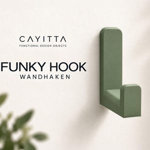 Könnte beinhalten: Ein salbeigrüner Wandhaken mit abgerundetem L-förmigen Design. Der Text CAYITTA FUNCTIONAL DESIGN OBJECTS FUNKY HOOK WANDHAKEN ist links neben dem Haken aufgedruckt. Der Haken hat eine glatte, matte Oberfläche und eine vertikale Montageplatte.