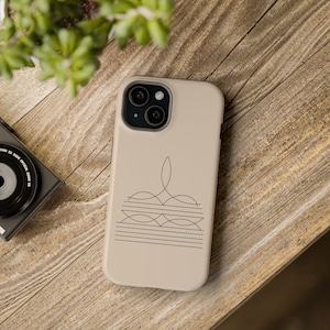 May include: A beige phone case with a geometric design in black. The design features a series of lines and curves that create a symmetrical pattern.