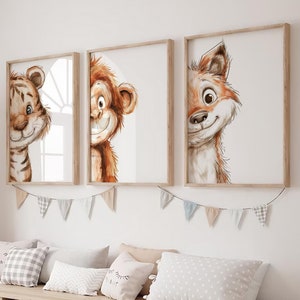 Puede incluir: Tres ilustraciones enmarcadas de un tigre, un mono y un zorro asomándose por detrás del marco. Los marcos son de madera clara y las ilustraciones son de estilo acuarela. Los marcos están colgados en una pared blanca sobre un banco de madera con contenedores de almacenamiento.