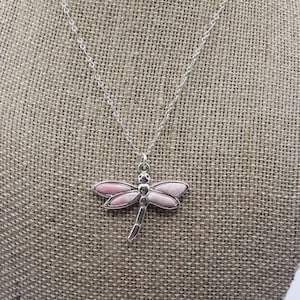 May include: A silver chain necklace with a pink dragonfly pendant.