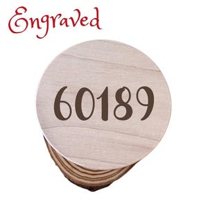 May include: A round wooden coaster with the number 60189 engraved on it. The coaster is made of light wood with a natural grain pattern.