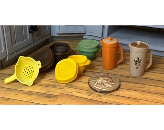 May include: A collection of vintage kitchenware in various colors, including a yellow strainer, brown and yellow containers, and orange and beige pitchers. A silver coin is also present.